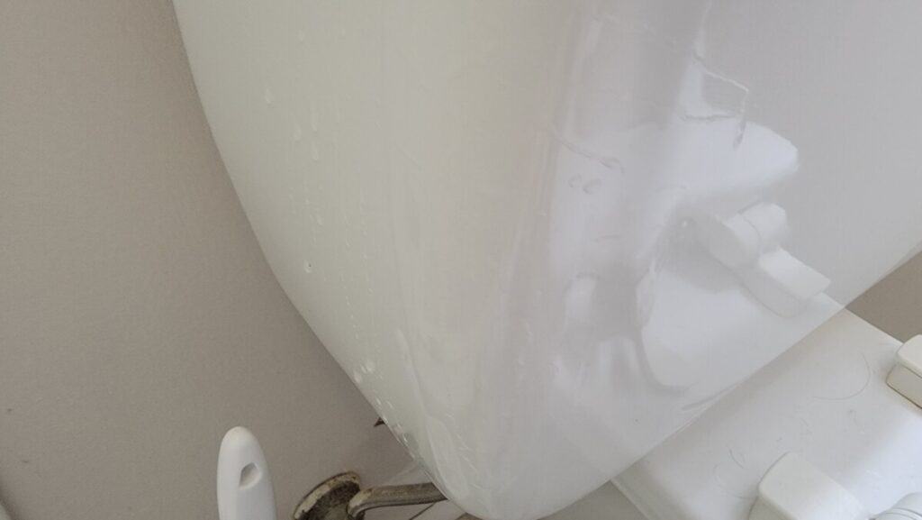 image showing condensation on the outside of a toilet tank causing water to form on the floor below.