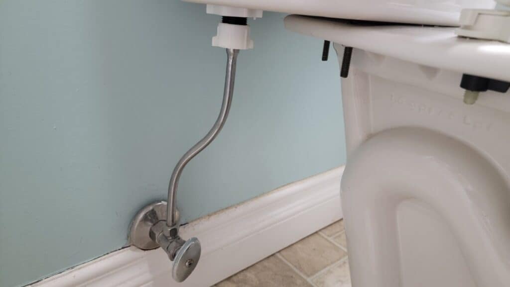 Image showing the water supply line to the toilet which could be one of the reasons there's water spraying behind a toilet.