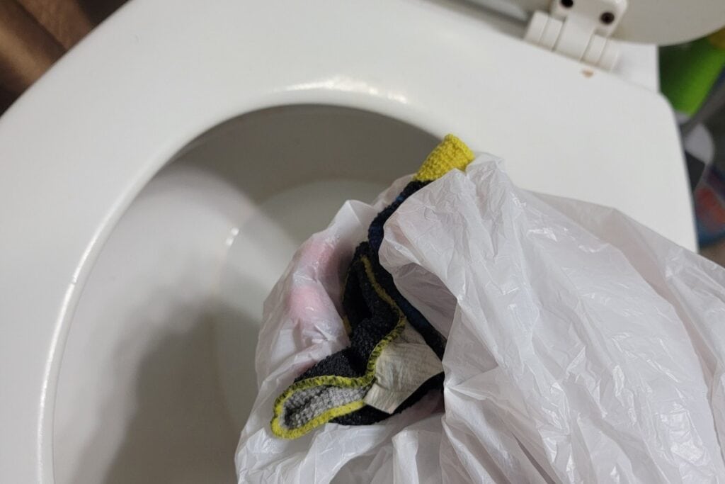 image showing the author retrieving a flushed washrag by hand using a plastic bag to keep clean